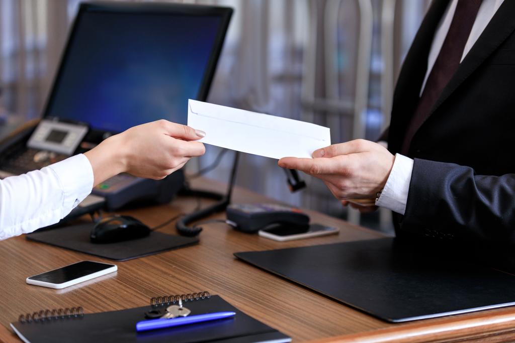 обрезанный образ регистратора, дающего конверт бизнесмену в отеле
 - Фото, изображение