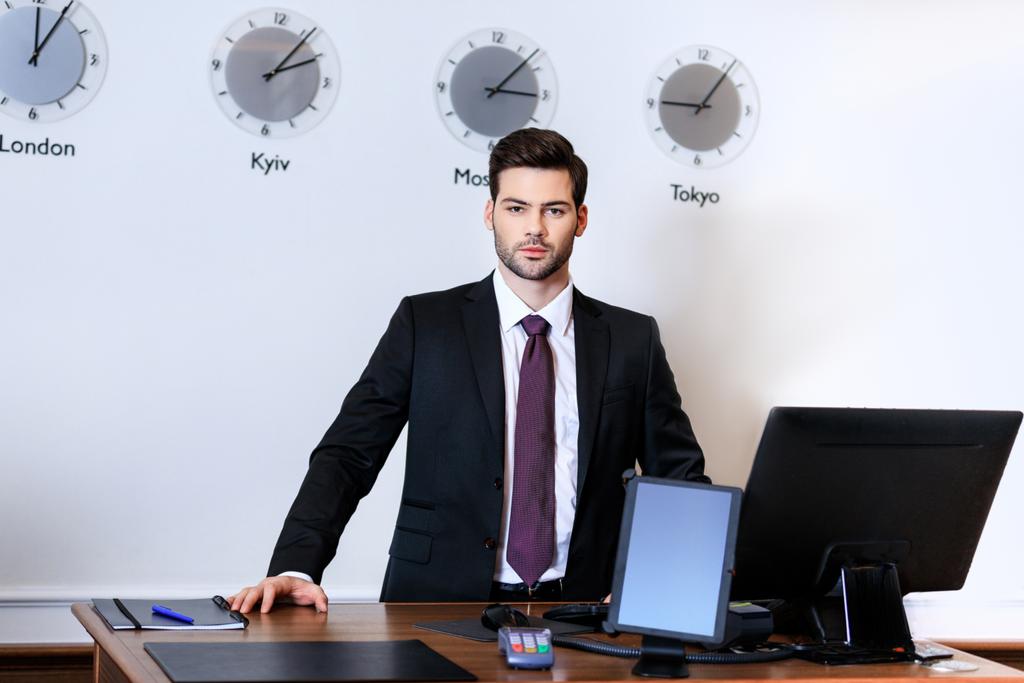 handsome receptionist standing at reception desk in hotel - Photo, Image
