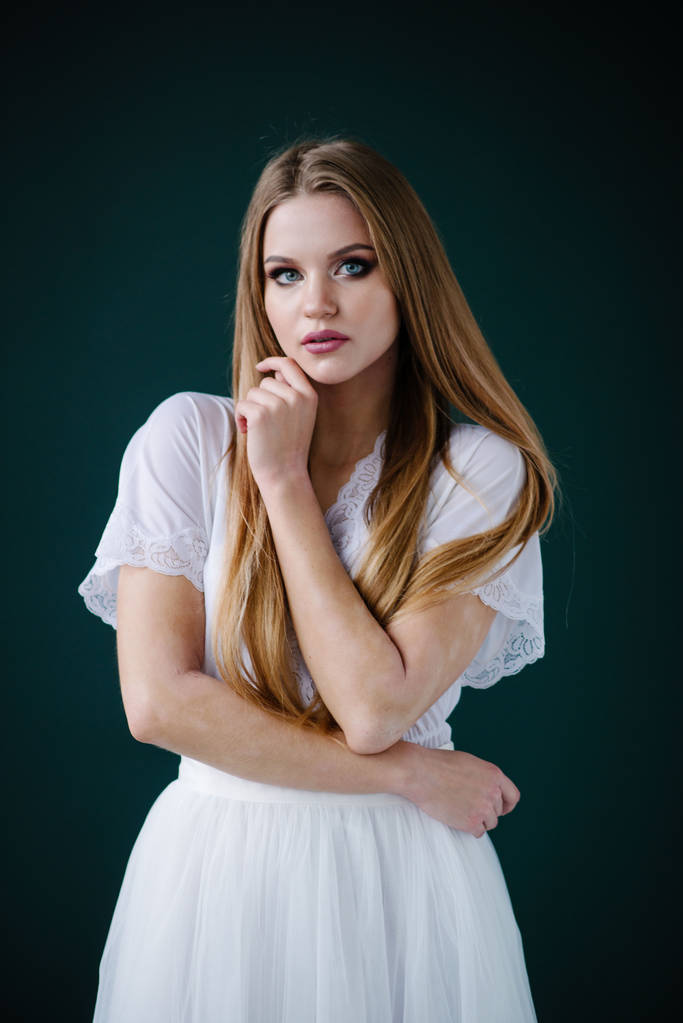 schöne junge Frau mit Make-up in weißem Kleid posiert im Studio - Foto, Bild