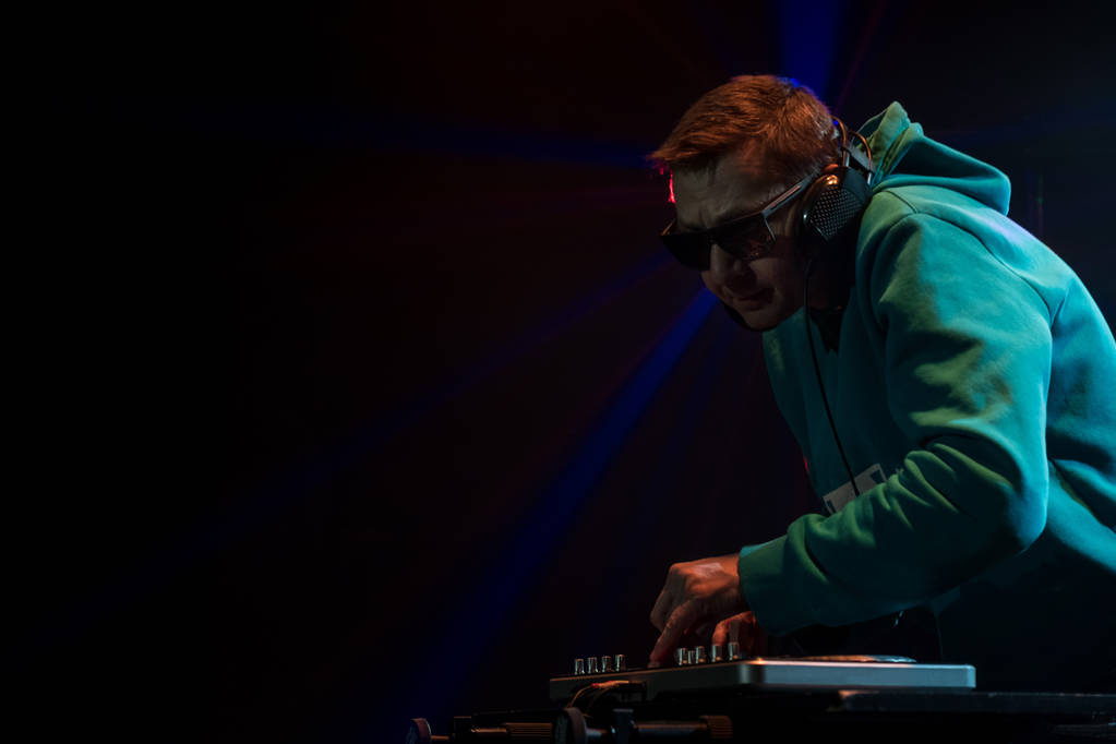 DJ work in a nightclub. Disco light in the club. DJ behind the turntable. - Photo, Image