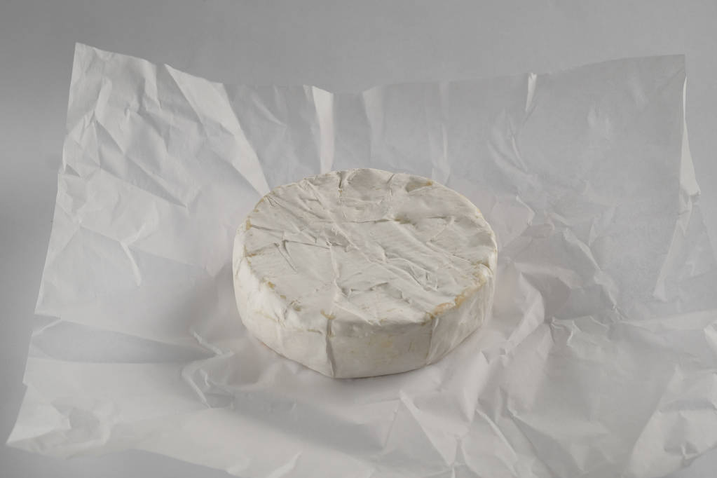 Nahaufnahme von leckerem Camembert-Käse auf weißem Papier Hintergrund  - Foto, Bild