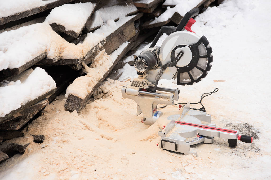 Sägeblatt und Brennholz mit Schnee bedeckt - Foto, Bild