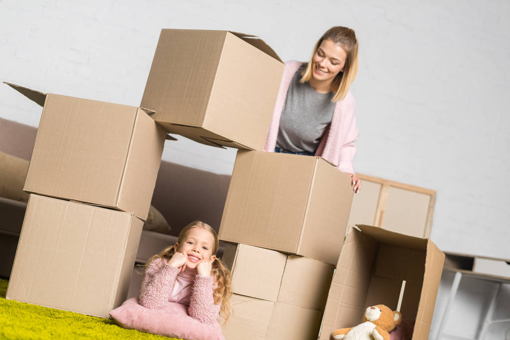 madre e hija se divierten con cajas de cartón mientras se mudan a casa
 - Foto, Imagen