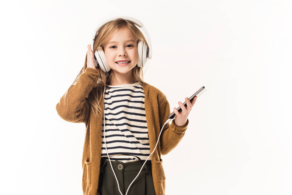 愛らしい小さな子音楽を聴くヘッドフォンと白で隔離のスマート フォン - 写真・画像