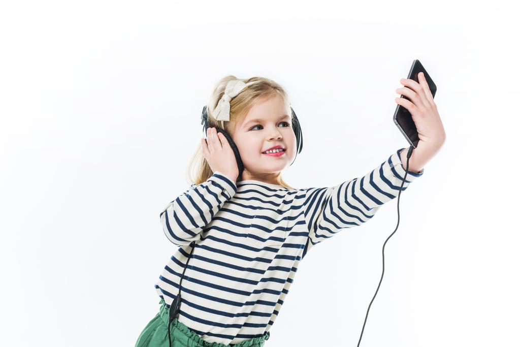 αξιολάτρευτο μικρό παιδί με ακουστικά λήψη selfie που απομονώνονται σε λευκό - Φωτογραφία, εικόνα