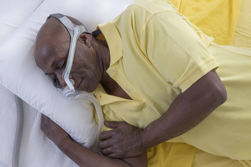 Gesundheitskonzept, afrikanisch, amerikanisch Mann mit obstruktiver Schlafapnoe schlafend gut mit cpap Maschine, Mann im Bett liegend mit cpap Maske, auf weißem Hintergrund - Foto, Bild
