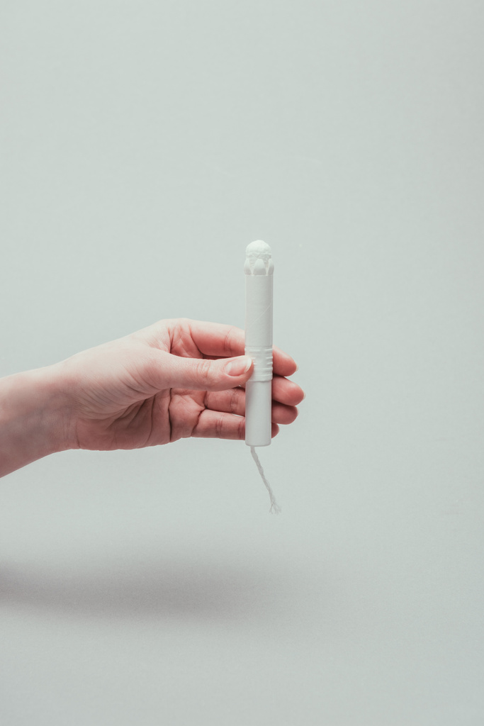 cropped shot of woman holding tampon in hand isolated on grey - Photo, Image