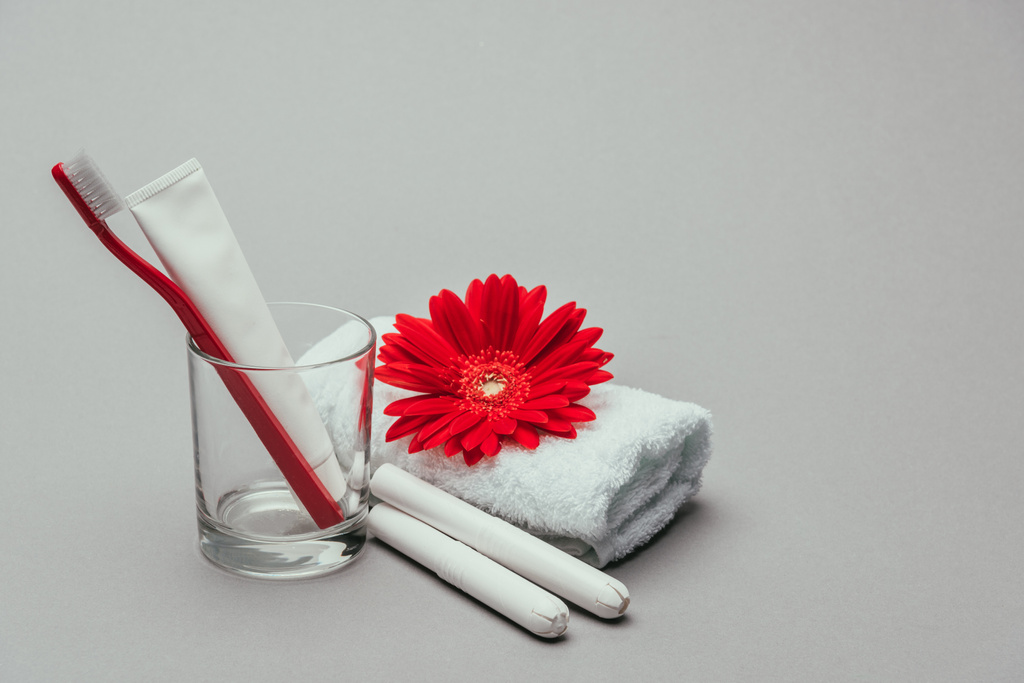 закрыть вид на гигиенические принадлежности, цветок и полотенце изолированы на сером
 - Фото, изображение