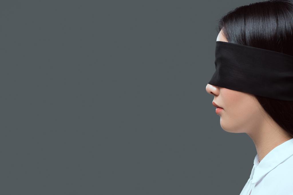 a fiatal nő visel fekete bekötött szemmel, elszigetelt szürke oldalnézete  - Fotó, kép