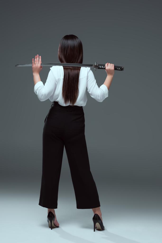 visão traseira da mulher segurando katana nos ombros em cinza
  - Foto, Imagem