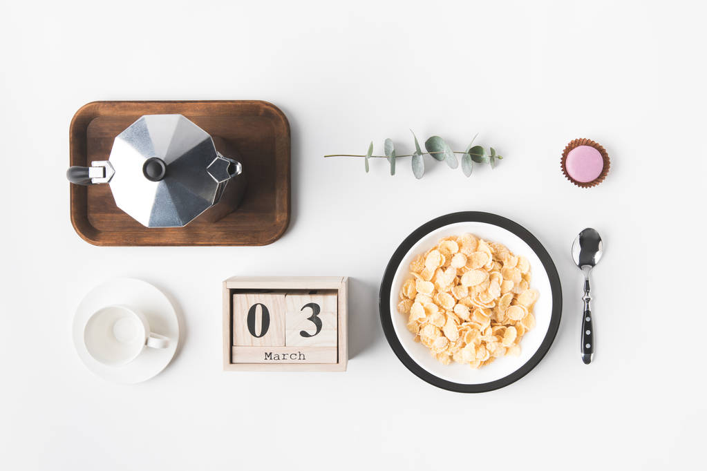 flat lay com flocos de milho na tigela para o café da manhã, cafeteira e xícara de café na superfície branca
 - Foto, Imagem