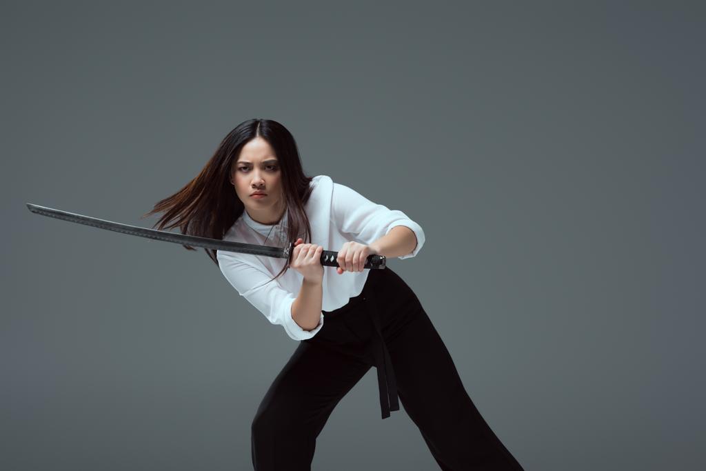 mladá asijská žena bojuje s katana meč izolované Grey  - Fotografie, Obrázek
