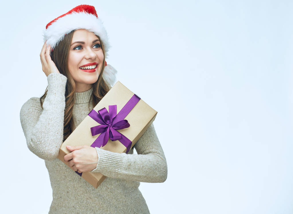 Beautiful surprised woman wearing Santa hat holding gift box  - Photo, Image