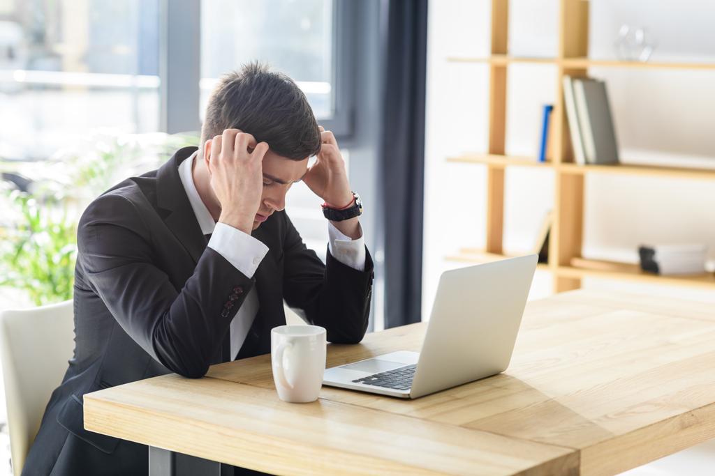 Jungunternehmer leidet unter Kopfschmerzen bei der Arbeit am Laptop - Foto, Bild