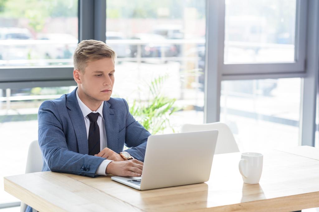 Jeune homme d'affaires regardant l'écran d'ordinateur portable dans le bureau moderne
   - Photo, image