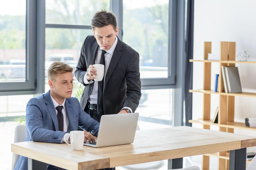 Deux hommes d'affaires discutent projet par ordinateur portable dans un bureau moderne
   - Photo, image