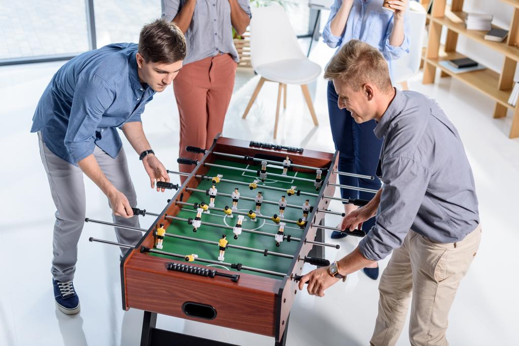 Бизнес-люди играют в настольный футбол в современном офисе
 - Фото, изображение