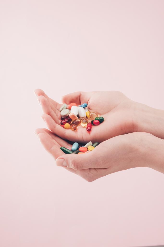 частковий вигляд жінки, що тримає таблетки в руках ізольовані на рожевому
 - Фото, зображення