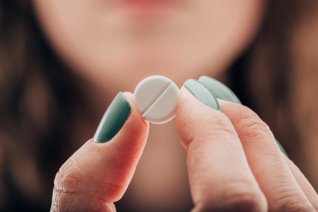 vista parcial de la mujer mostrando píldora en la mano
 - Foto, Imagen