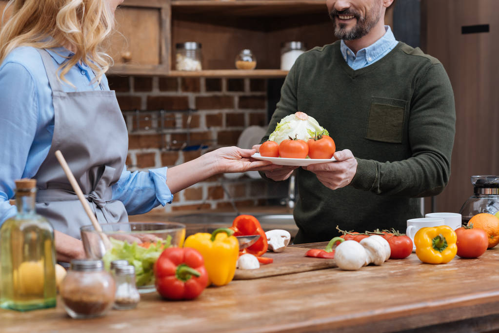 обрізане зображення дружини, що дає тарілку з овочами чоловікові
 - Фото, зображення