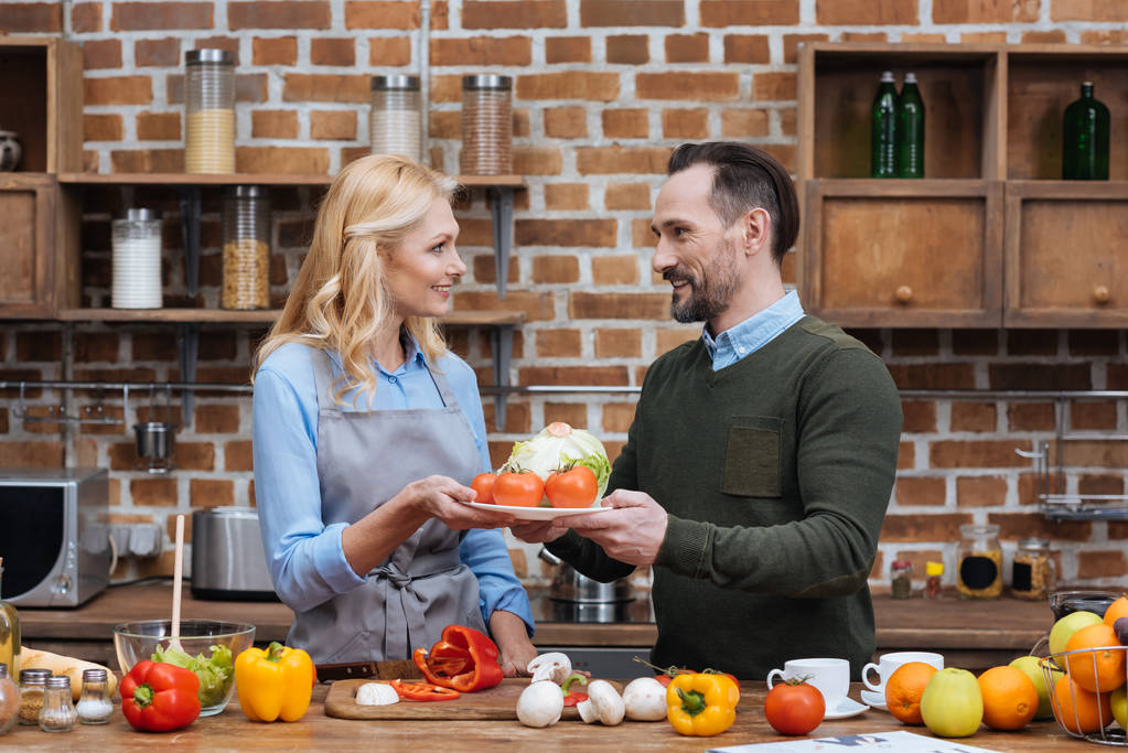 marido dando plato con verduras a la esposa
 - Foto, Imagen