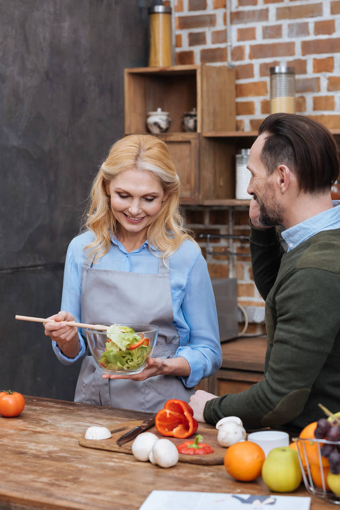 mosolygó felesége keverés konyhában saláta - Fotó, kép
