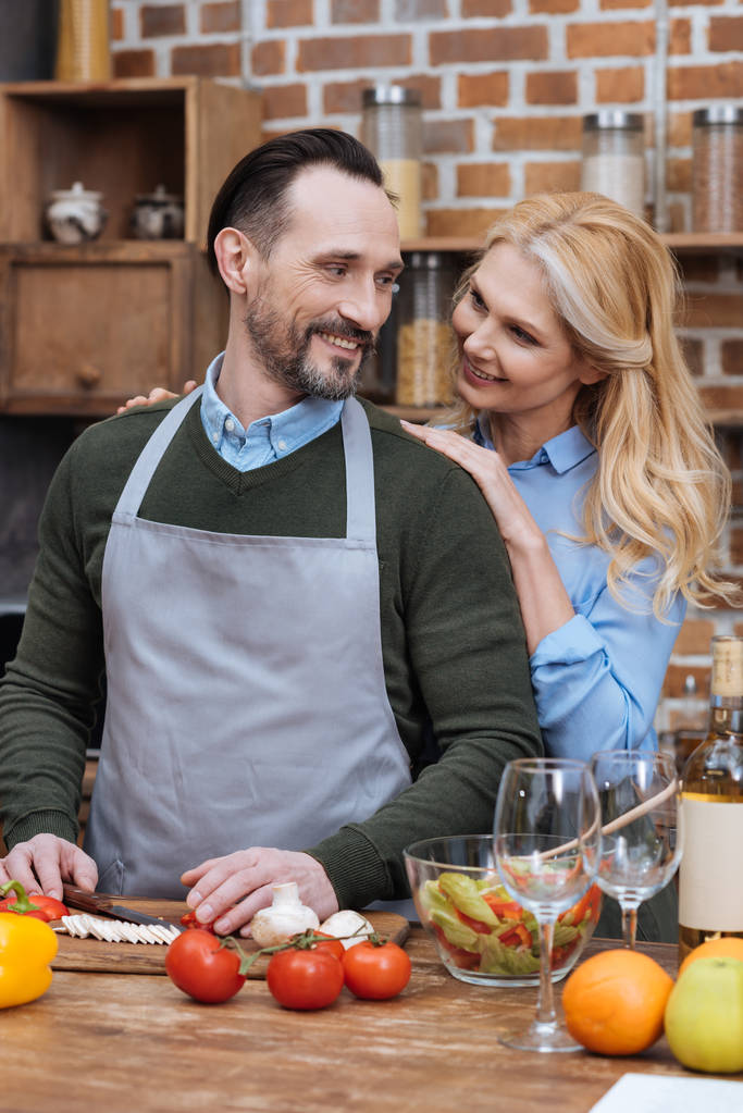 moglie abbracciare marito mentre cucina in cucina
 - Foto, immagini