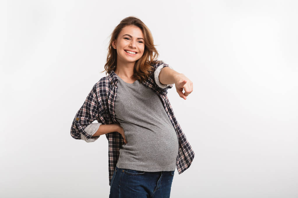 χαμογελώντας έγκυος γυναίκα δείχνει μακριά απομονωμένες σε γκρι - Φωτογραφία, εικόνα