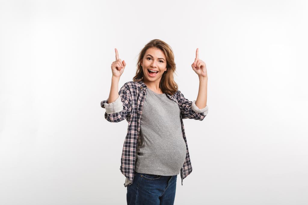 portrait of happy pregnant woman pointing up isolated on grey - Photo, Image