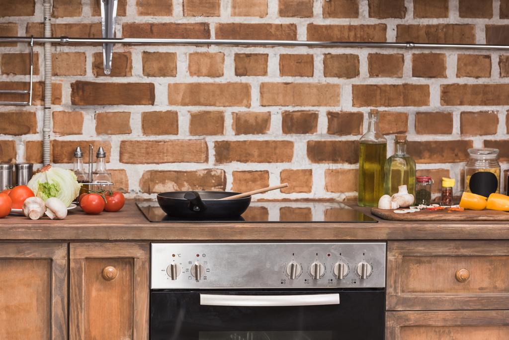 koekenpan en houten spatel op fornuis in de keuken - Foto, afbeelding