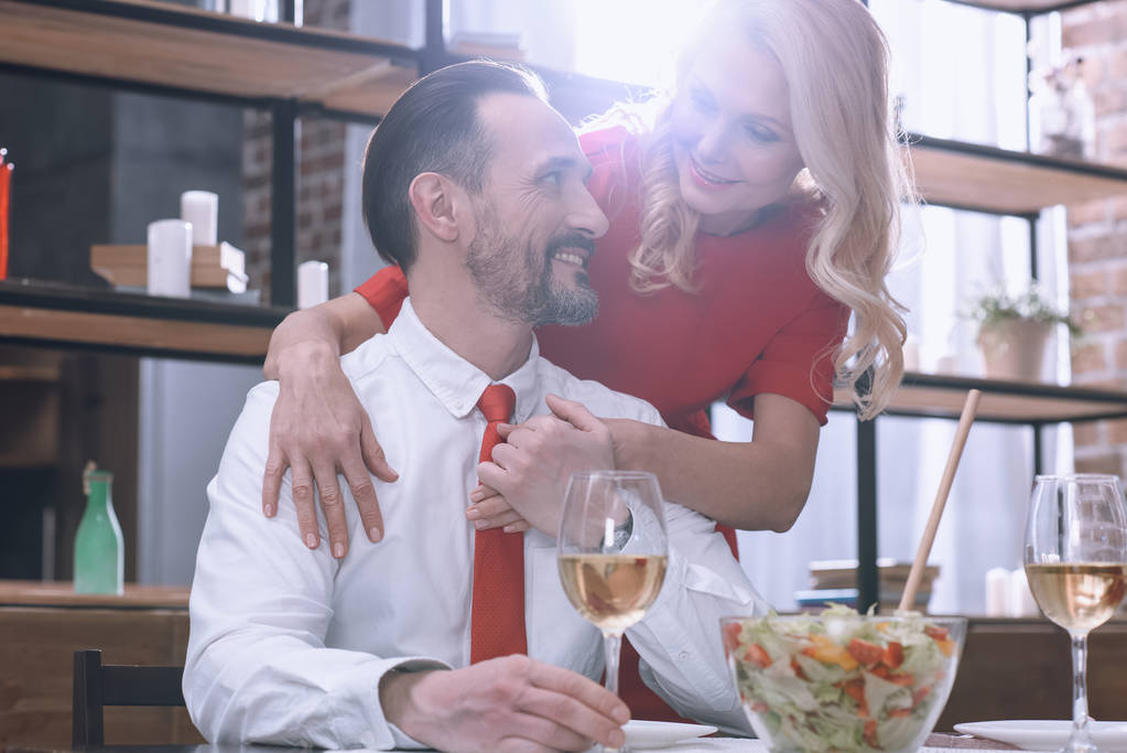 дружина обіймає чоловіка і вони тримають руки за романтичну вечерю
 - Фото, зображення