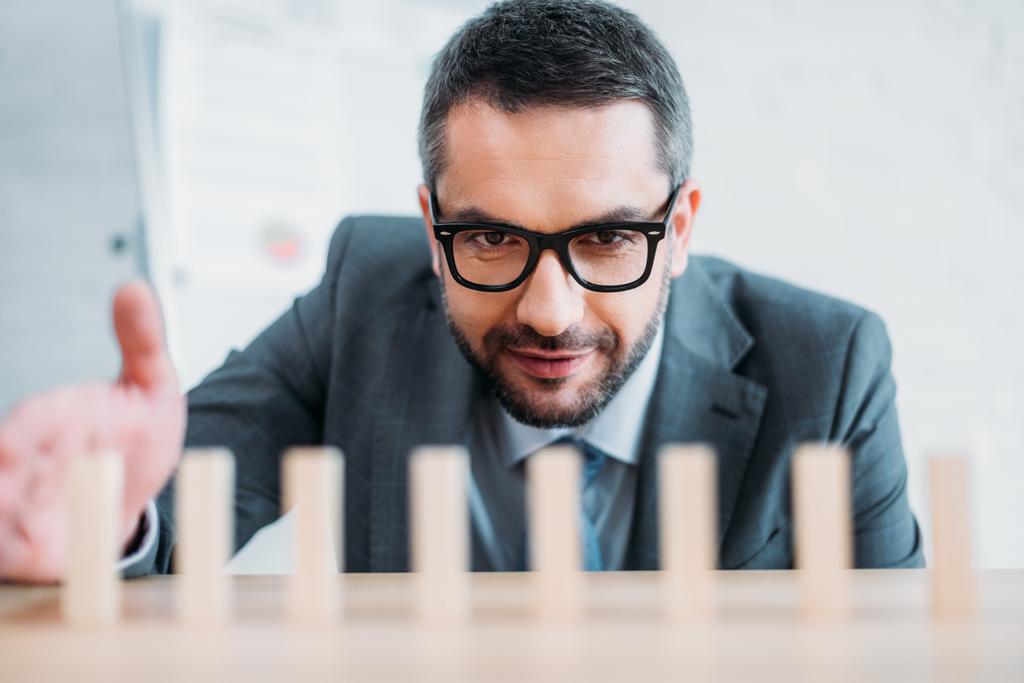 primer plano plano del hombre de negocios ensamblando bloques de madera en fila en la mesa de trabajo, concepto de efecto dominó
 - Foto, Imagen