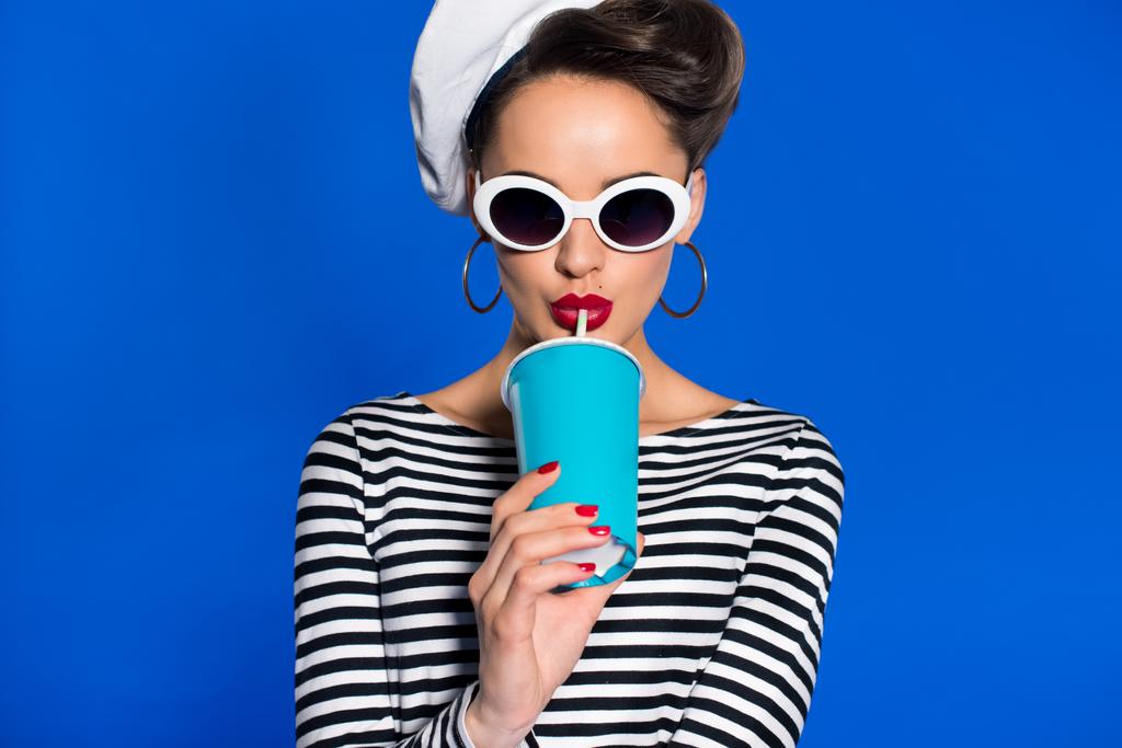 portrait de la jeune femme élégante avec boisson dans une tasse en papier isolé sur bleu
 - Photo, image