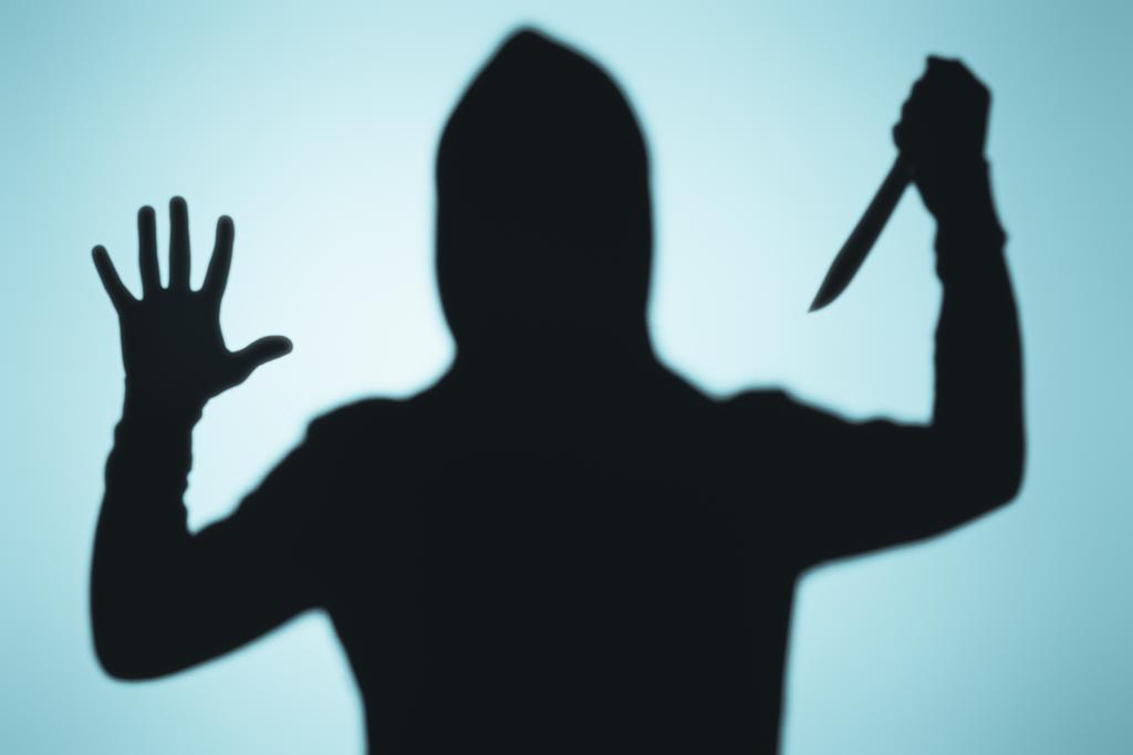 scary shadow of person in hood holding knife on blue - Photo, Image