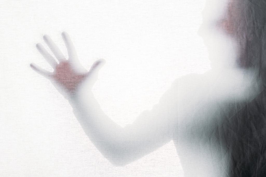 расплывчатый силуэт кричащего человека, касающегося матового стекла
 - Фото, изображение