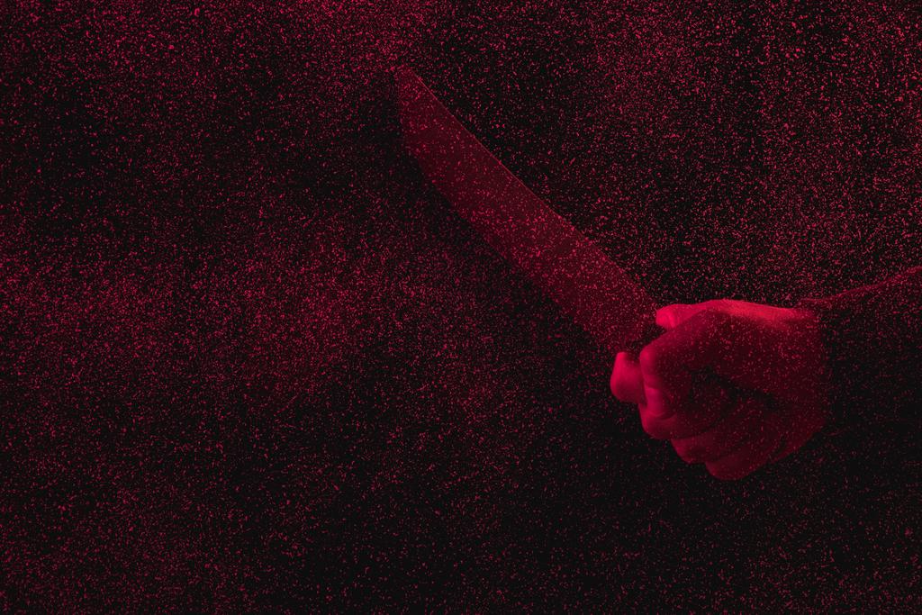 recortado tiro de hombre sosteniendo cuchillo en luz roja con fallos
  - Foto, imagen