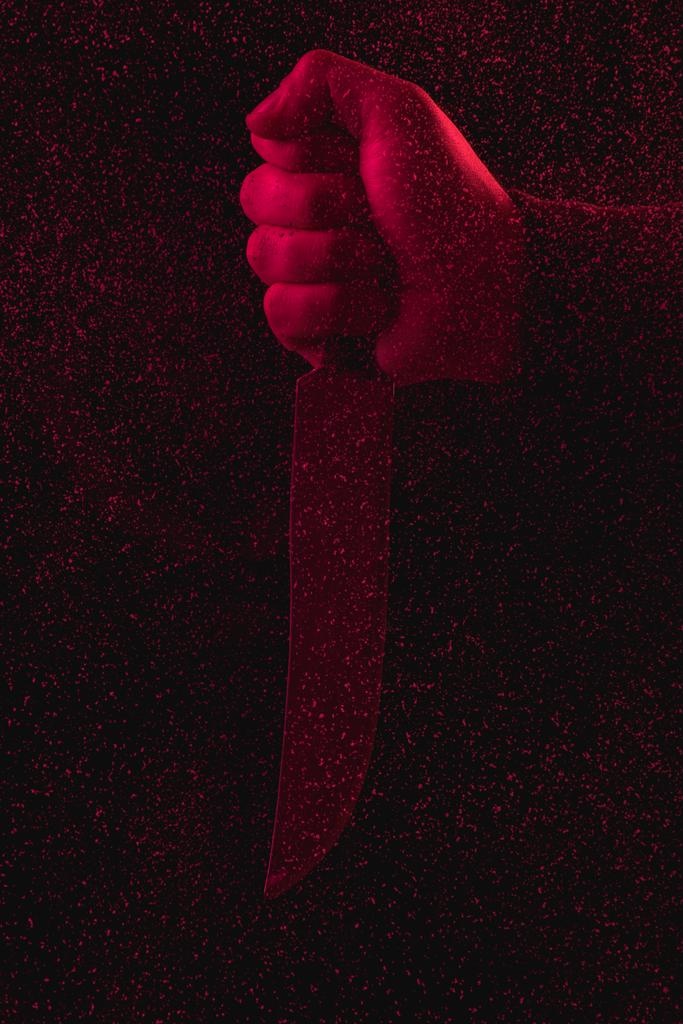 крупним планом частковий вид людини, що тримає ніж у червоному світлі
 - Фото, зображення