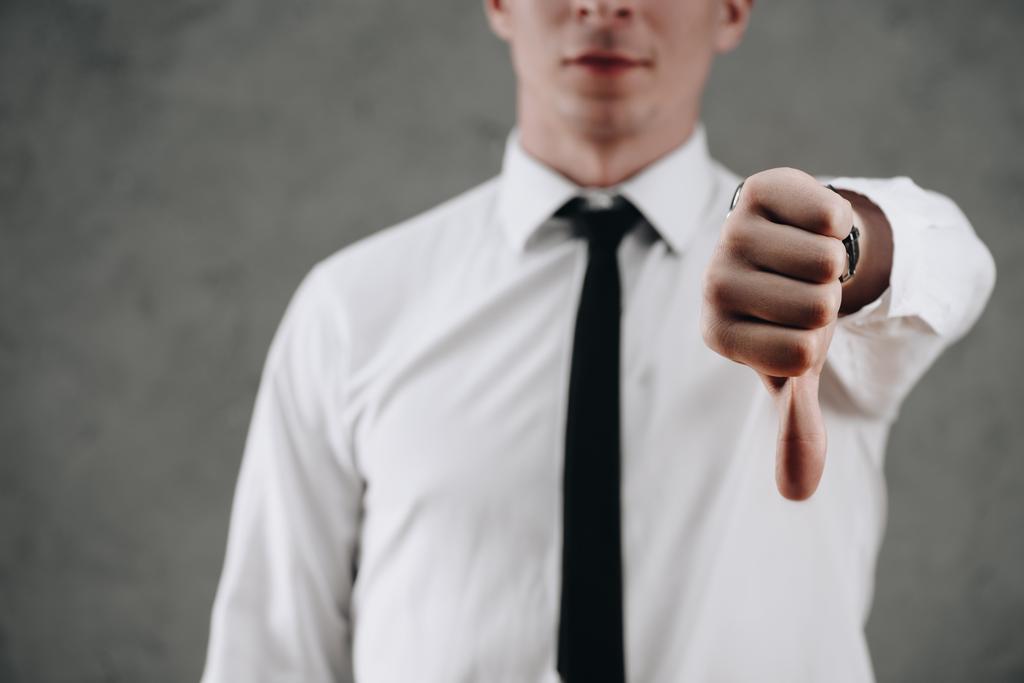 cropped shot of businessman showing thumb down on grey  - Photo, Image