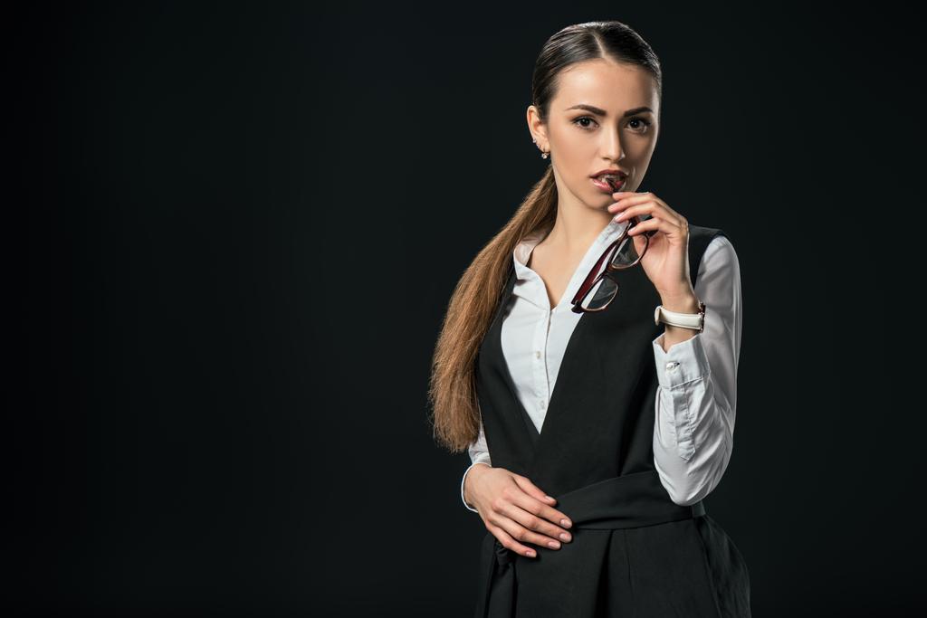 young beautiful businesswoman holding eyeglasses, isolated on black - Photo, Image