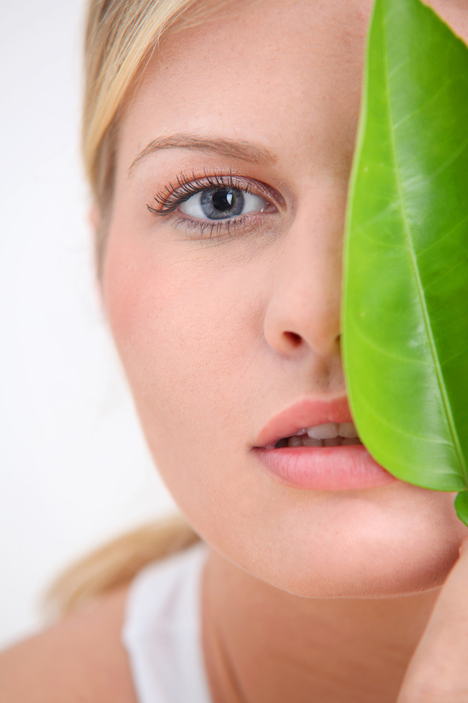 Close-up van mooie vrouw met groene plant blad - Foto, afbeelding