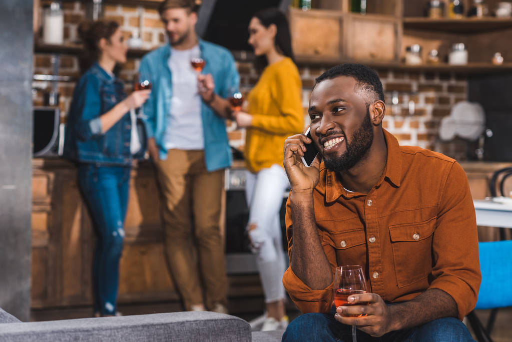 yanında smartphone arkasında şarap içme arkadaş sırasında konuşan gülümseyen Afrikalı-Amerikalı adam  - Fotoğraf, Görsel