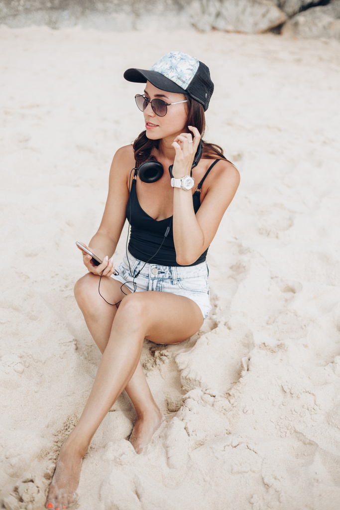 mulher usando smartphone ouvindo música com fones de ouvido na praia
 - Foto, Imagem