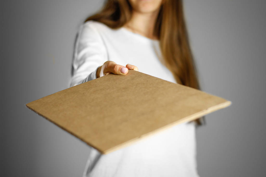 Молодая девушка в белом пиджаке держит кусок картона. Пре
 - Фото, изображение