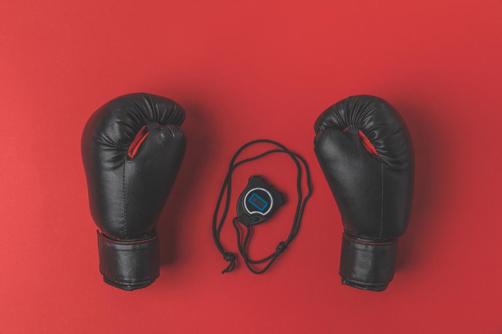 top view of boxing gloves with stopwatch on red tabletop - Photo, Image