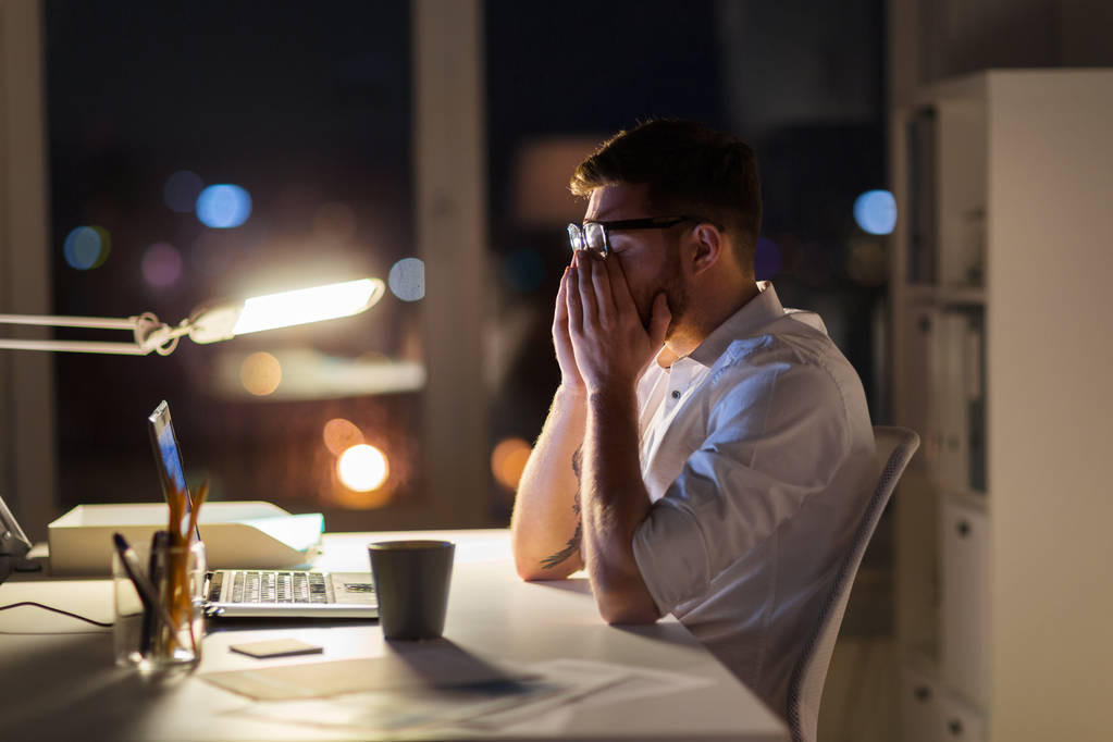 hombre de negocios cansado con portátil en la oficina de noche
 - Foto, imagen