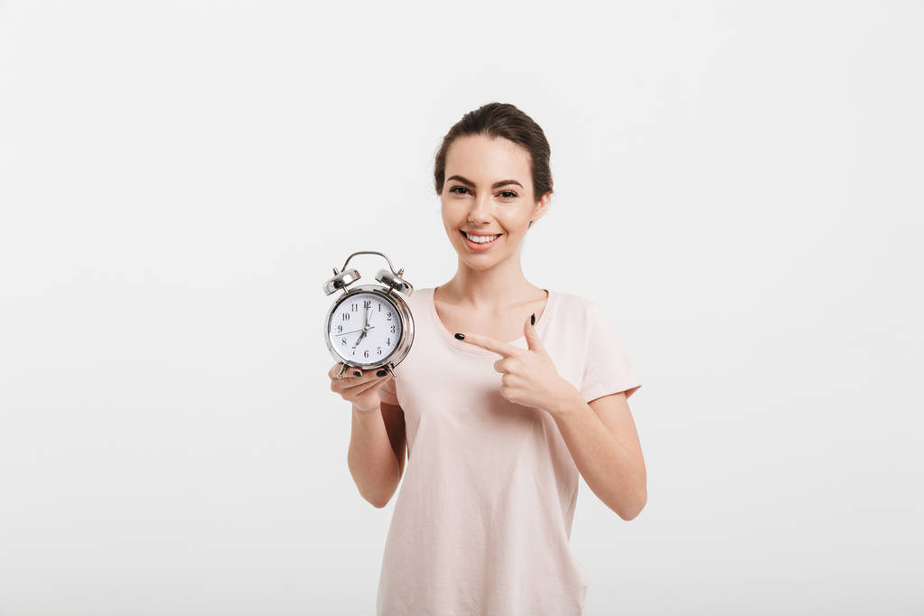 smiling girl pointing on alarm clock isolated on white - Photo, Image