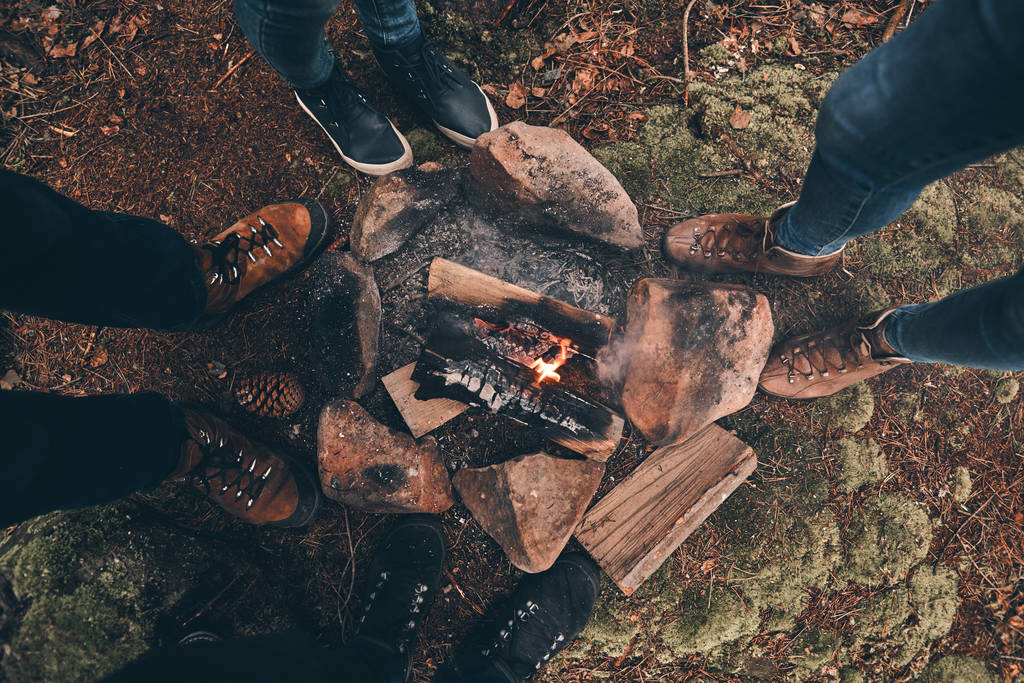 partial view of people standing around campfire in forest - Photo, Image