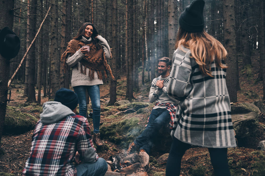 four tourist friends spending time at campfire in forest - Photo, Image