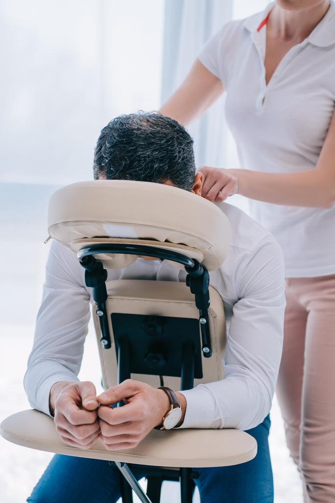 masseuse doen schouders massage op stoel op kantoor - Foto, afbeelding