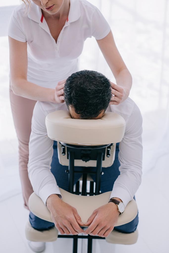 vysoký úhel pohledu masérka dělá masáž hlavy pro podnikatele - Fotografie, Obrázek